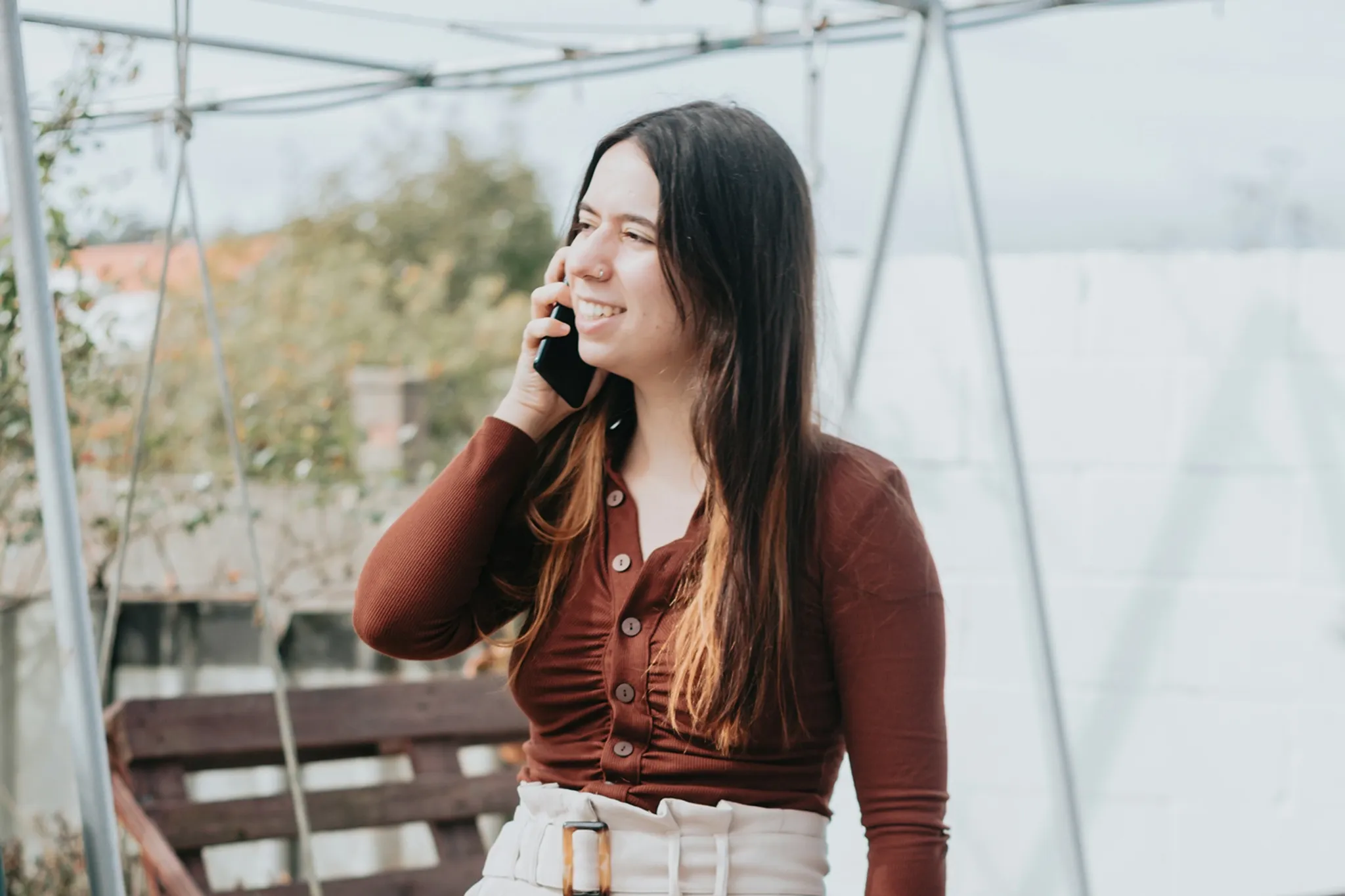 Junge Frau telefoniert im Garten mit einem Smartphone