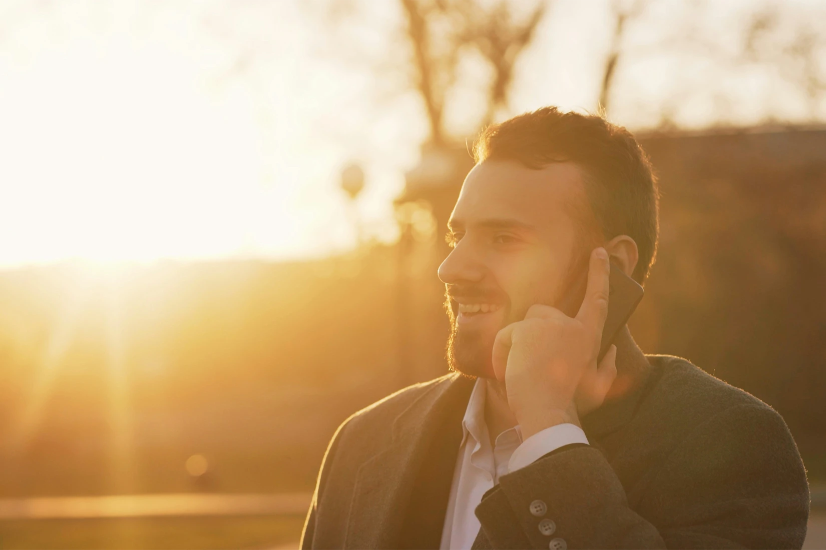 Geschäftsmann telefoniert mit Smartphone bei Sonnenuntergang