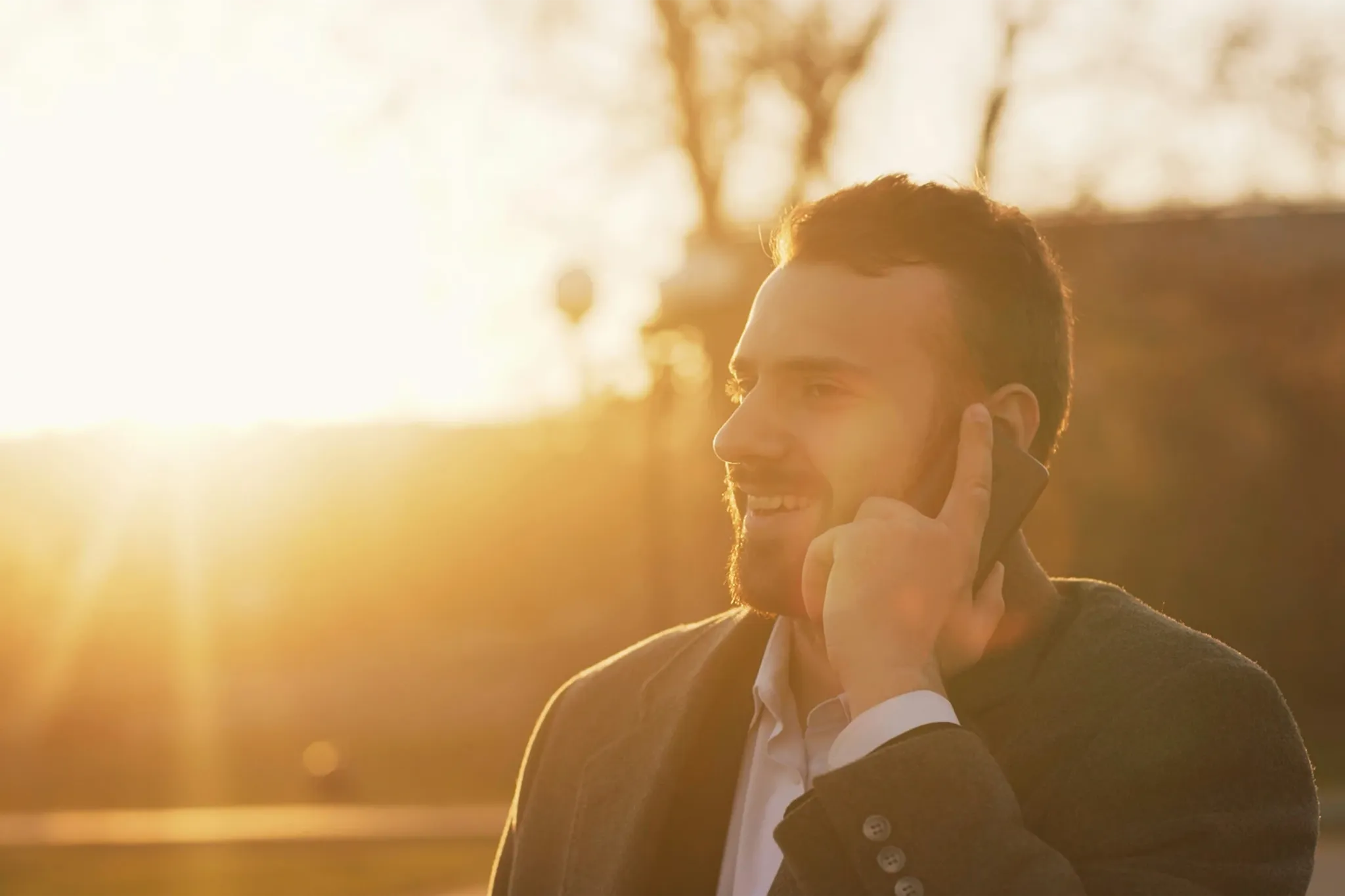Geschäftsmann telefoniert mit Smartphone bei Sonnenuntergang