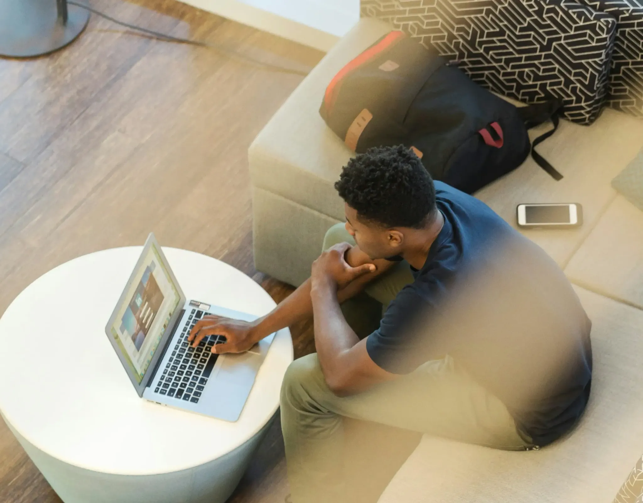 Mann arbeitet mit Laptop und Smartphone auf dem Sofa