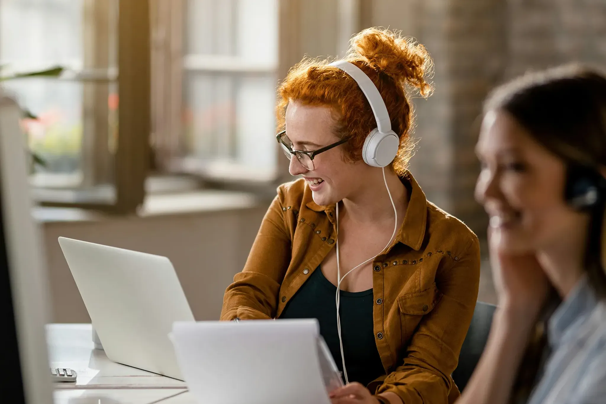 Mitarbeiterinnen im Callcenter telefonieren mit Headset vor Computer