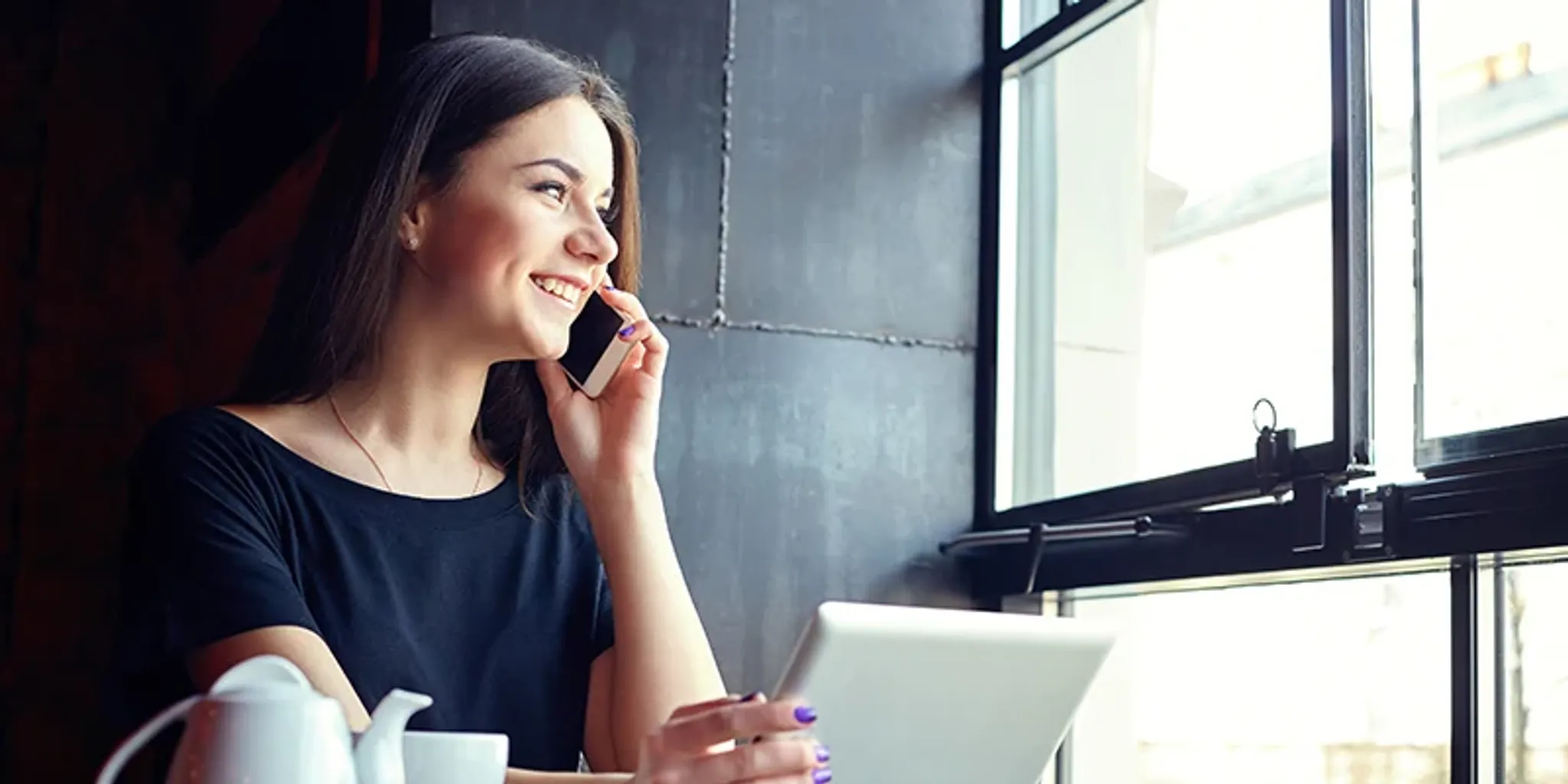 Frau telefoniert und sieht dabei aus dem Fenster