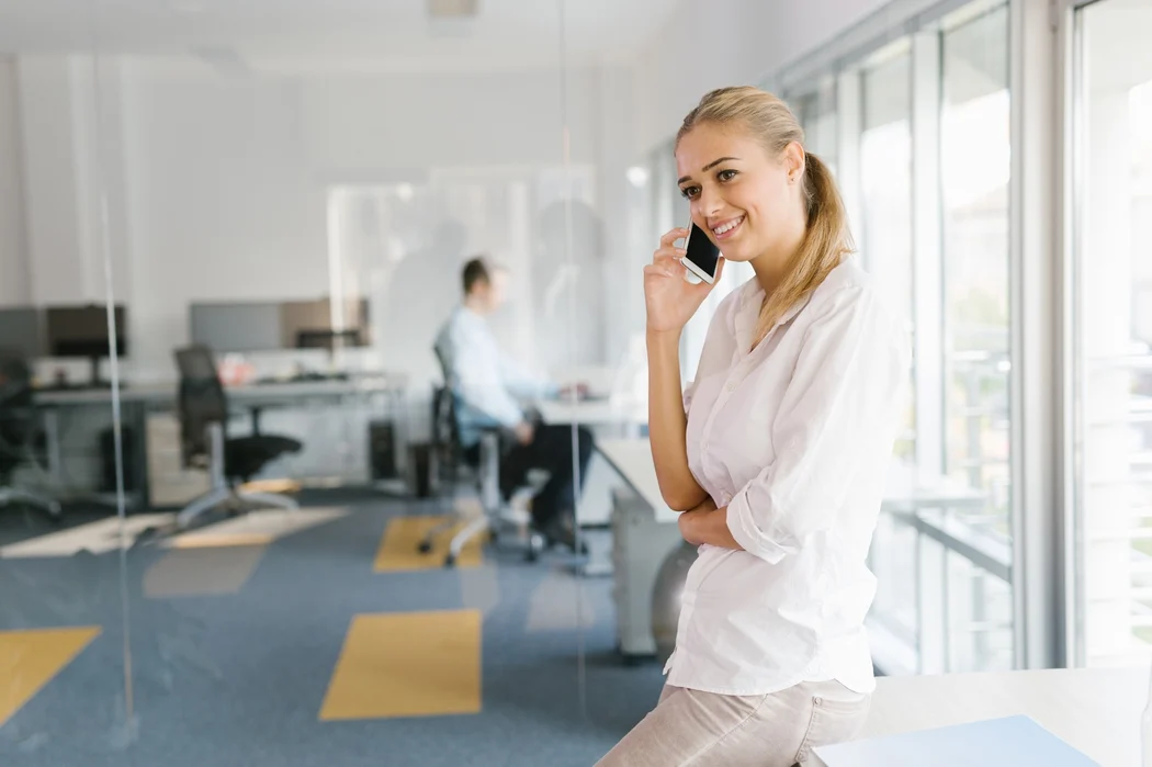 Frau telefoniert in Büro am Smartphone