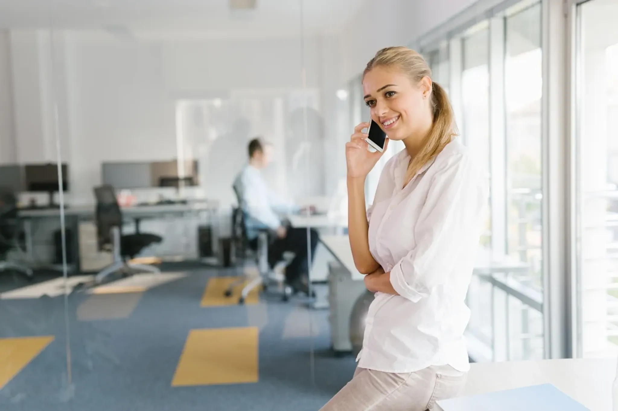 Frau telefoniert in Büro am Smartphone