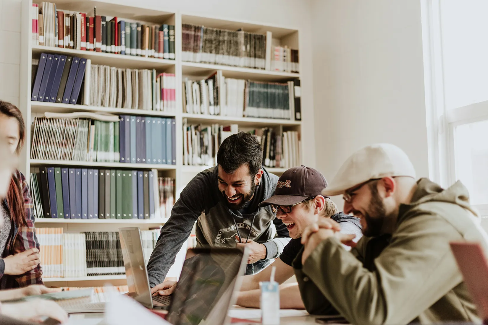 Junge Männer lachen bei Meeting vor einem Laptop