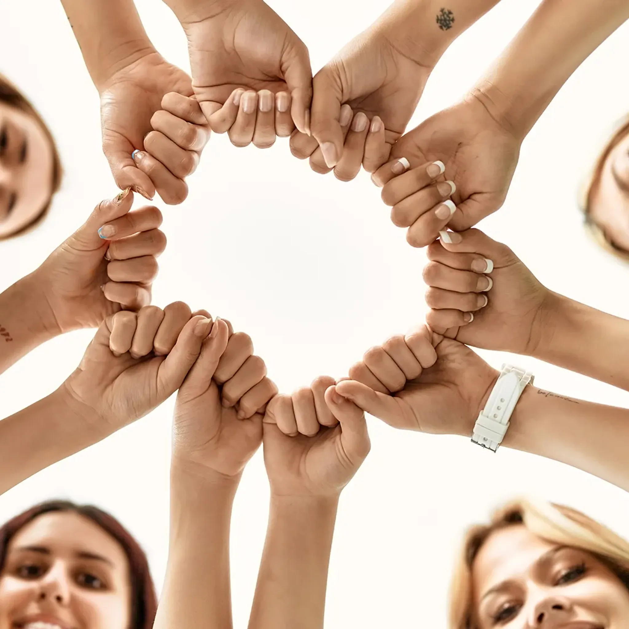 Team an Frauen steht im Kreis und streckt Fäuste zusammen